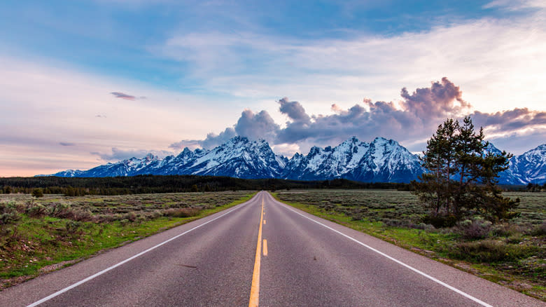 A road stretches toward the snow-capped Grand Teton Mountains in Wyoming.