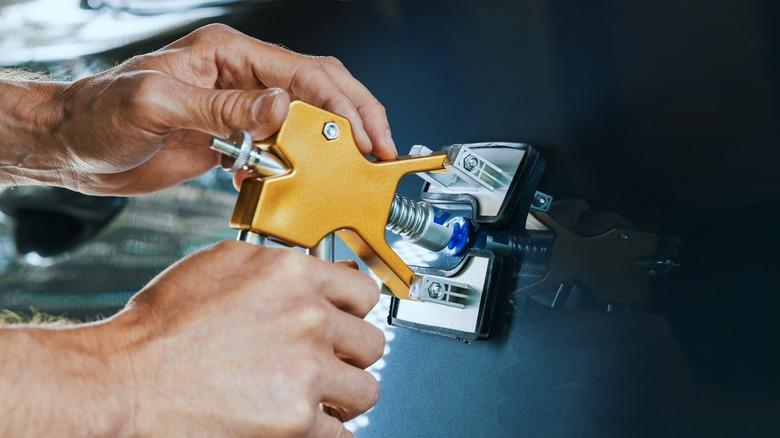 A technician removing a dent from a car door using paintless dent repair