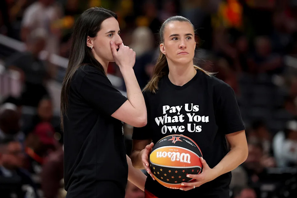 INDIANAPOLIS, INDIANA - JULY 19: Caitlin Clark #22 of the Indiana Fever and Sabrina Ionescu #20 of the New York Liberty wears a shirt saying