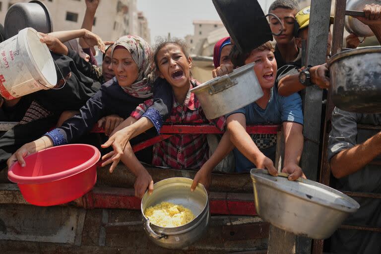 Palestinos tratan de conseguir comida en un comedor benéfico en la Ciudad de Gaza