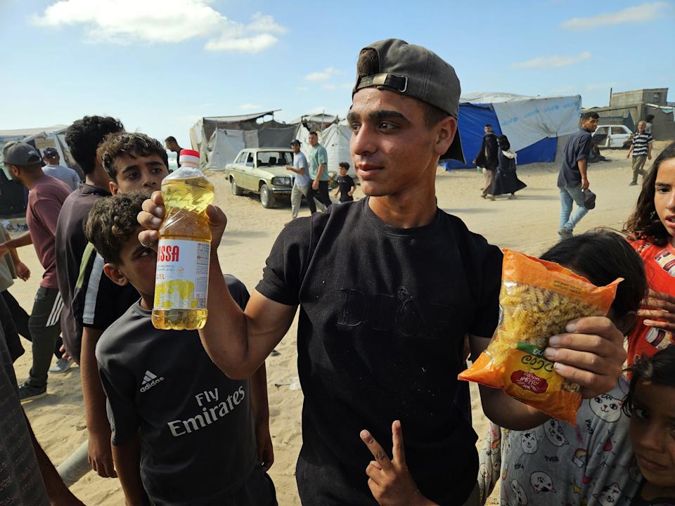 Un chico palestino muestra una botella de aceite de cocinar y un kilo de pasta