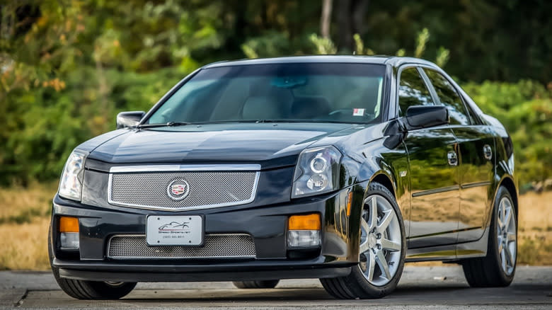 A black first generation Cadillac CTS-V parked in front of out-of-focus bushes