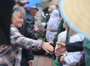Canadians and Americans reach across the border to shake hands in an event celebrating friendship between the two nations at the International Peace Garden on Aug. 9, 2025. (Photo by Mary Steurer/North Dakota Monitor)