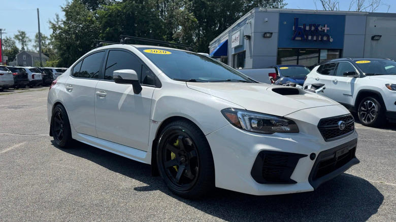 a white subaru parked on a used car lot in the sun