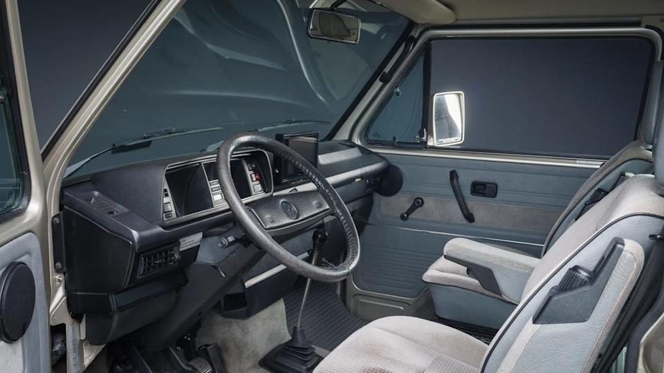 front interior view of van cabin showing steering wheel, dashboard, and two front seats.