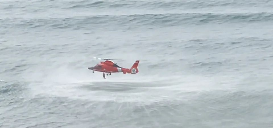The rescue swimmer drops from the helicopter to save the girl.