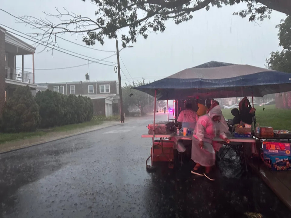 A crowd huddles underneath a tent to escape the rain at a Wilmington Play Streets event on July 8, 2025, at Harlan Elementary School.