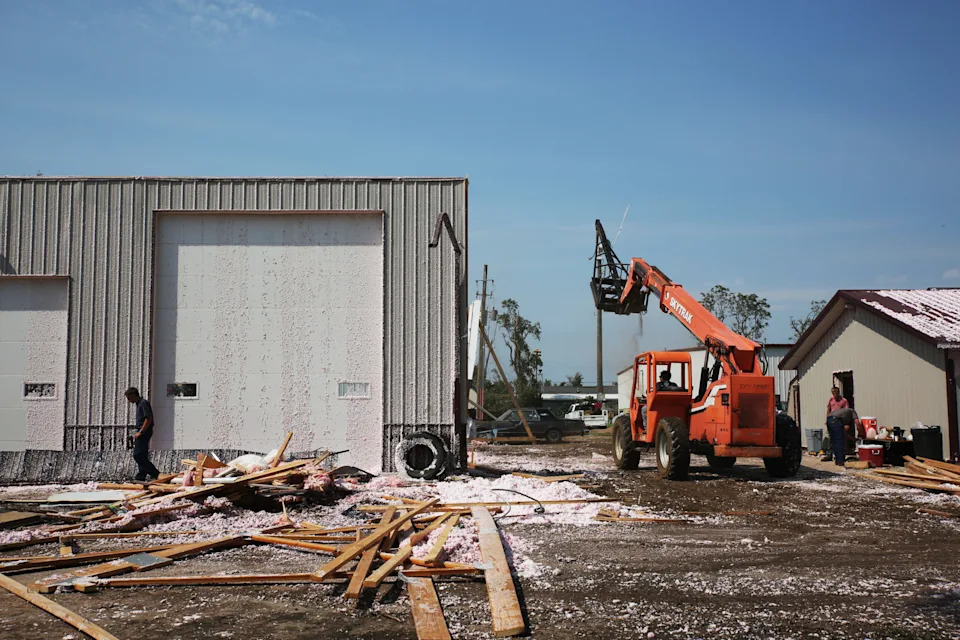 Volunteers help clean up damaged warehouse in Hudson on Tuesday, July 29, 2025 after severe weather blew the roof off of the building Monday evening. The system damaged trees, homes and other structures. (Makenzie Huber/South Dakota Searchlight)