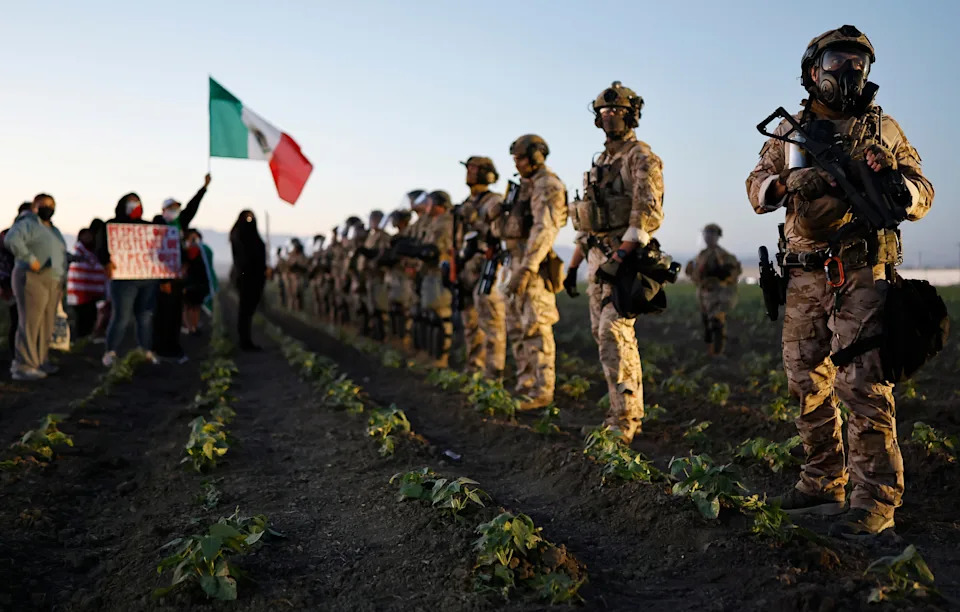 Federal agents and National Guard members block people protesting an ICE immigration raid at a nearby licensed cannabis farm on July 10, 2025 near Camarillo, California. Protestors stood off with federal agents for hours outside the farm in the farmworker community in Ventura County.