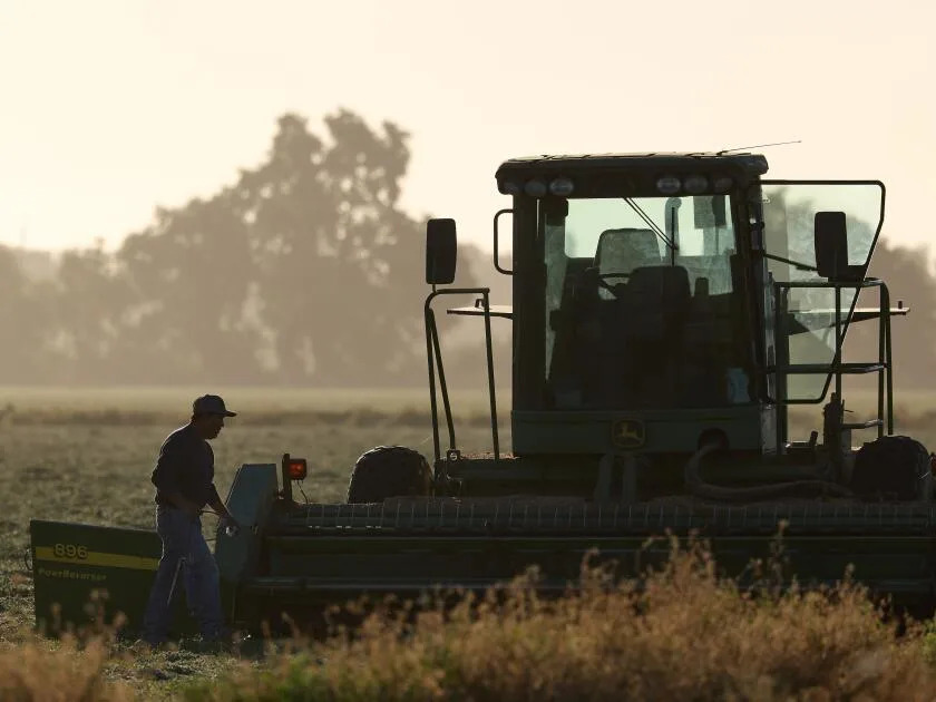 A farmworker makes repairs to a tractor in a recently harvested field Friday in Woodland.