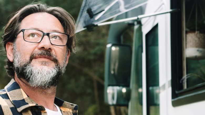 Middle-aged man looking skyward while standing beside an rv