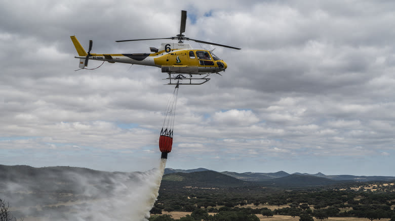An INFOEX helicopter drops water on the wildfire near Aliseda on July 11, 2025 in Cáceres, Spain. The fire that broke out in the Sierra de San Pedro mountain has affected areas of pastureland and scrubland near Aliseda