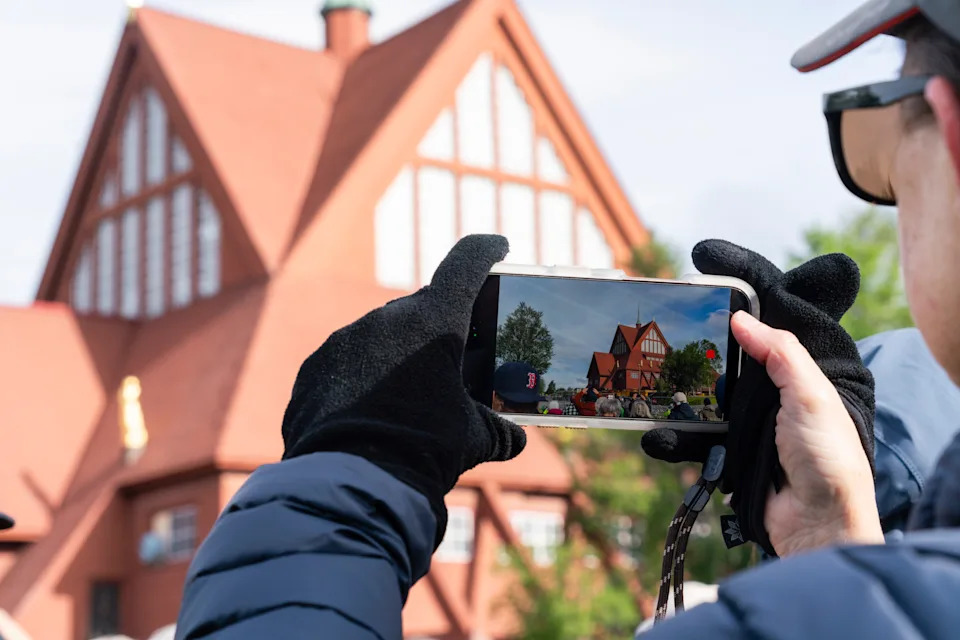 A person takes a photograph of a wooden church with their phone.