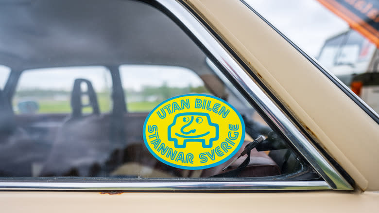 Yellow and blue bumper sticker on the window glass of a vintage car