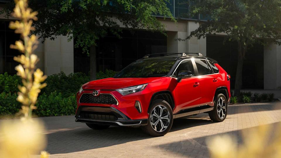 Static front 3/4 shot of a red 2025 Toyota RAV4 PHEV XSE parked outside of a modern building.