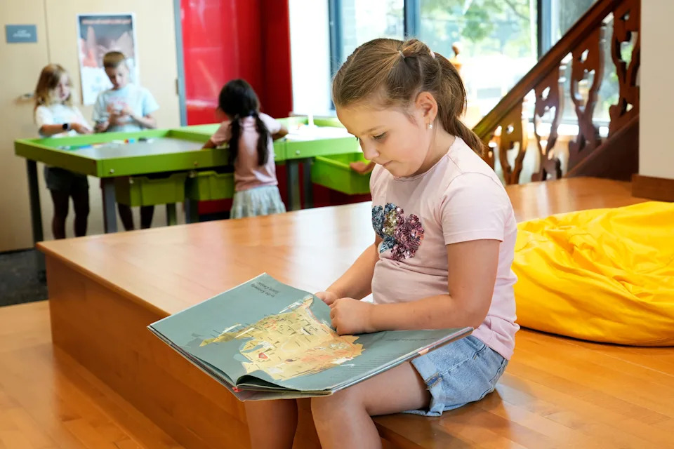 Former first-grader Josie, 7, reads in the library at Lincoln Elementary in Wauwatosa, where she is attending the summer school program.