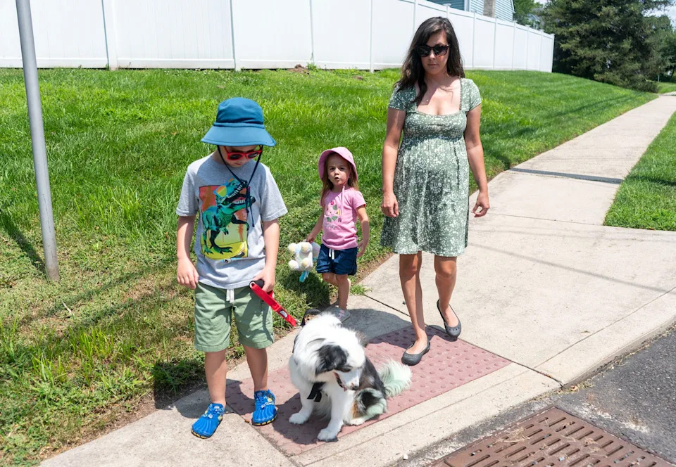 Lincoln Bergey, 8, left, who has a visual impairment and autism, waits at the corner with his service dog, Marley, a miniature Australian Shepherd, sister, Alaina, 3, and mom, Tara Bergey, right, in Sellersville, Pennsylvania, on July 24, 2025.