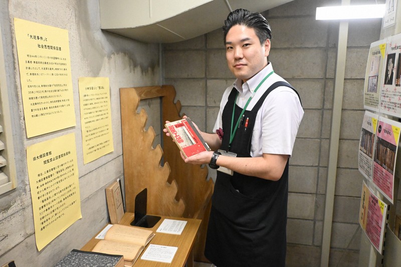「発禁本」だった小林多喜二の「蟹工船」を手にする三康図書館司書の新屋朝貴さん＝東京都港区芝公園4の三康図書館で2025年7月31日午後0時5分、原奈摘撮影