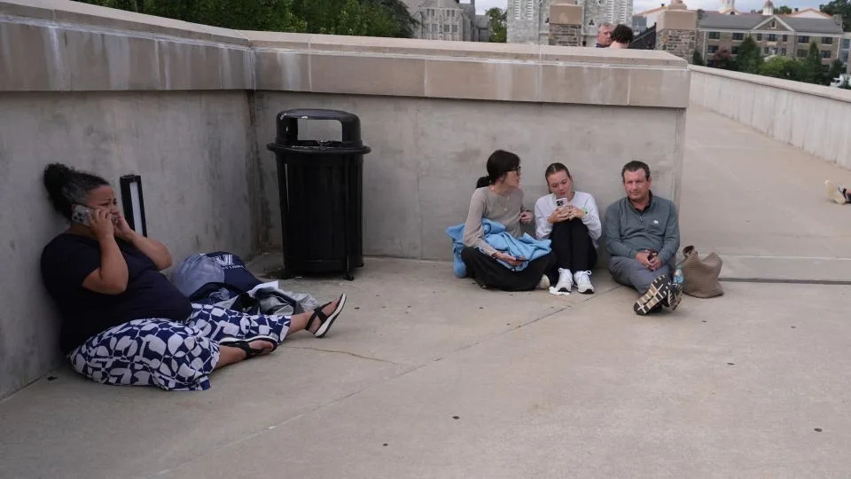 Students shelter behind a wall at the Villanova University campus where an active shooter was reported. - Matt Slocum/AP