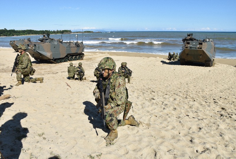 日米共同訓練で海から砂浜に乗り上げた水陸両用車から降りて、小銃を手に配置につく陸上自衛隊の隊員ら＝鹿児島県徳之島町の万田海岸で2022年11月18日、山口桂子撮影