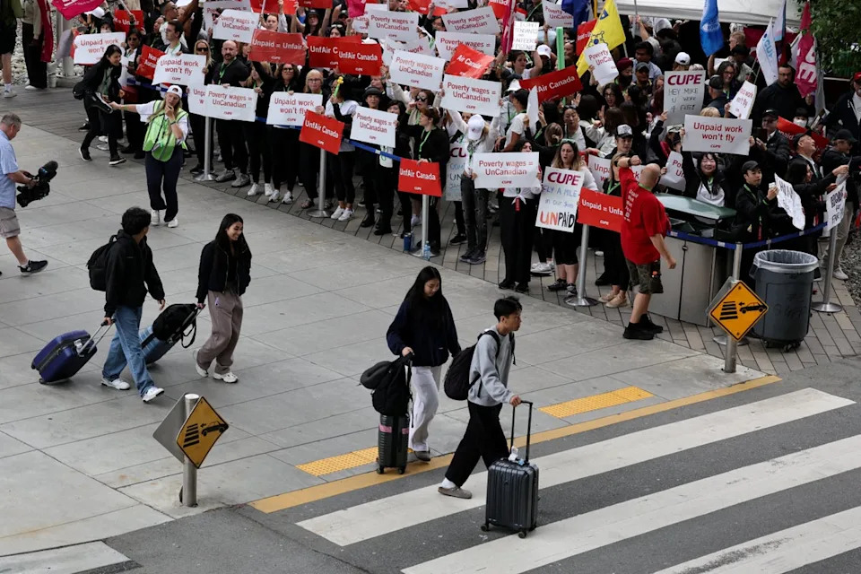 Passengers walk in front of demonstrators holding placards as Air Canada flight attendants said they will remain on strike and challenge a return-to-work order they called unconstitutional (Reuters)