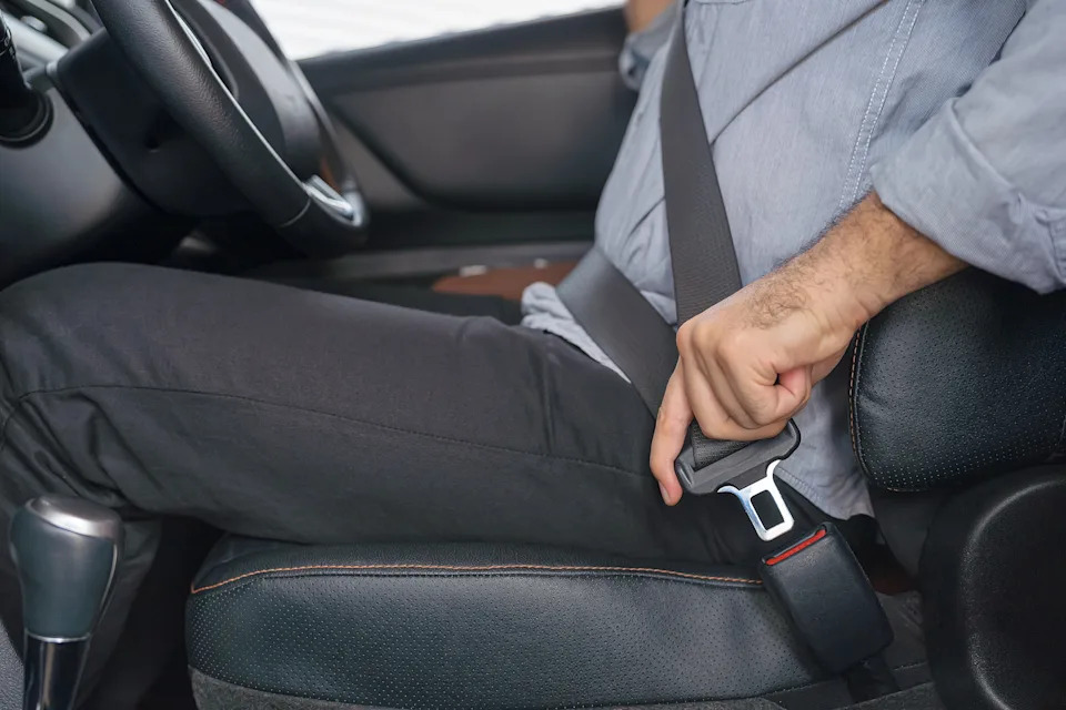 Person in a car fastening their seatbelt, highlighting safety and responsible driving