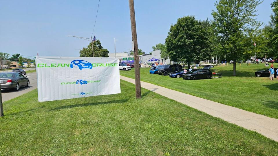 banner advertising clean cruise event with parked vehicles in the background