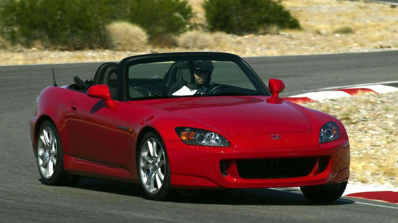 Honda S2000 in red driving around a track on a sunny day