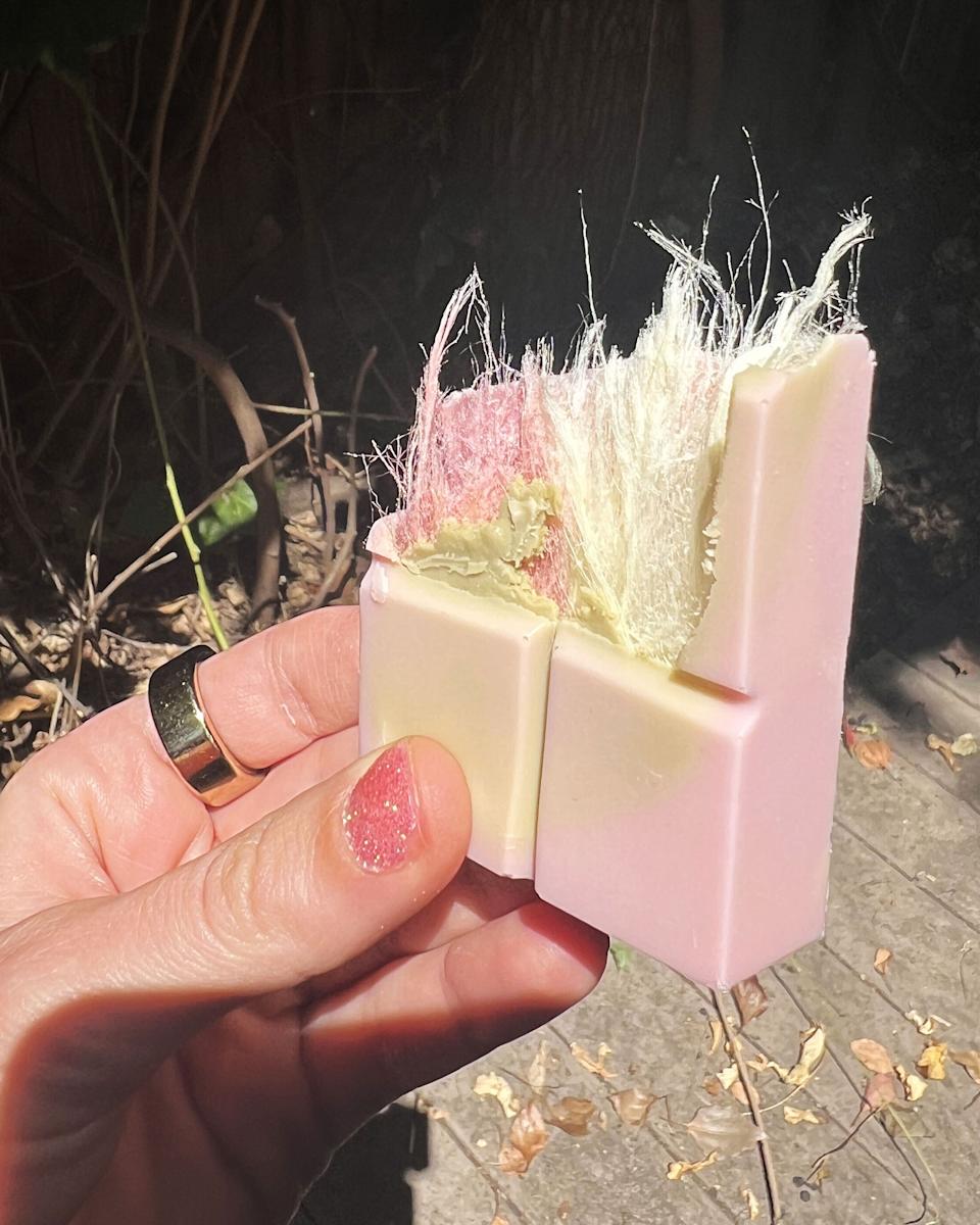 A hand holds a piece of the new angel hair chocolate bar, giving a glimpse of the cotton candy inside.
