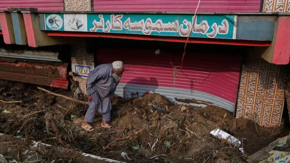 A shopkeeper removes mud and debris in front of his shop following Friday's flash flooding at a market in Pir Baba, an area of Buner district, Pakistan, on August 17, 2025. - Muhammad Sajjad/AP