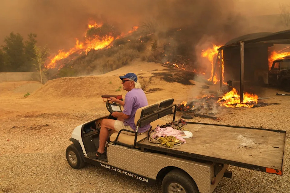 A resident was pictured fleeing the fire on a golf buggy. Evacuation orders are in place in the area. (AP)