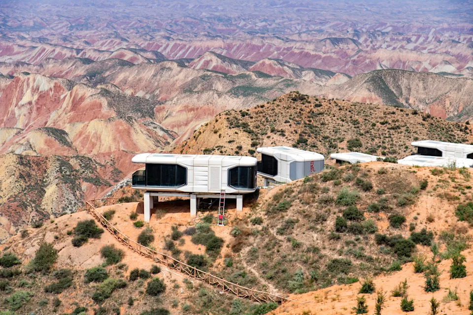 A set of futuristic-looking dwellings, mounted along a ridge overlooking desert hills.