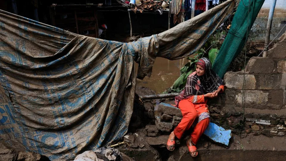 A girl sits outside of her family home, which was damaged following heavy rains and flooding in Pacha Kalay Bazar, in Buner district, Pakistan, on August 18, 2025. - Akhtar Soomro/Reuters