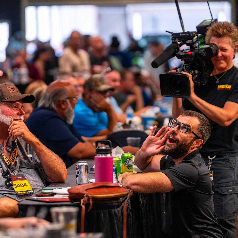 Mecum employee assisting bidders at Mecum collector cars auction.