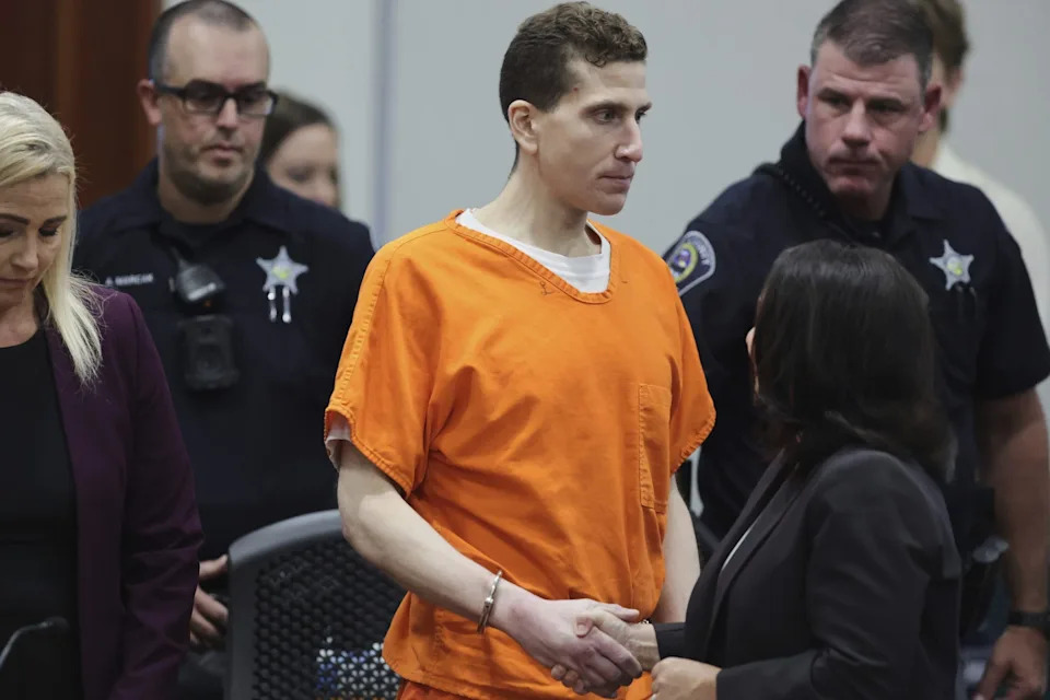 Kohberger in shackles and an orange jail jumpsuit shakes the hand of attorney Elisa Massoth