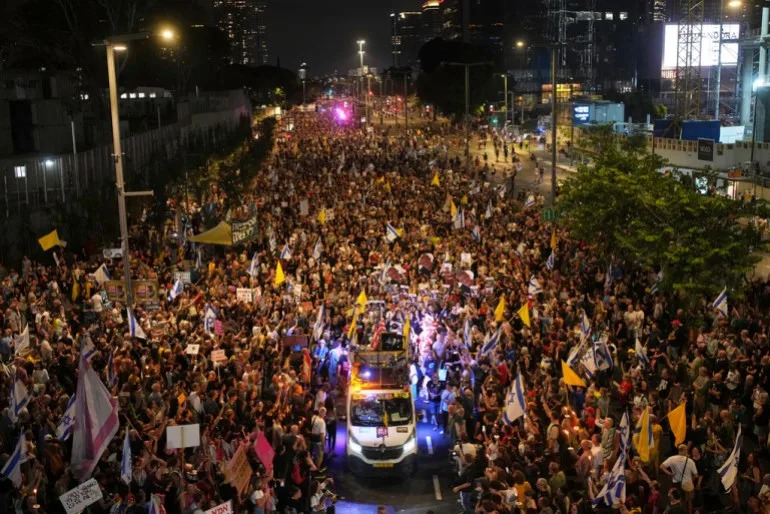 a large crowd of people walk in a street at night
