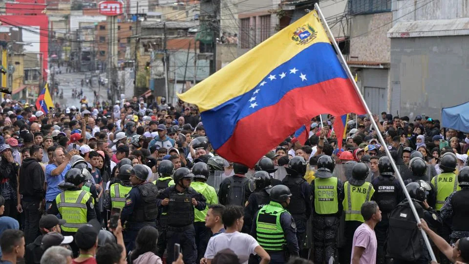 A man waves a Venezuelan flag as demonstrators clash with police officers during a protest against President Nicolas Maduro's government in Caracas on July 29, 2024, a day after the Venezuelan presidential election. - Yuri Cortez/AFP/Getty Images/File