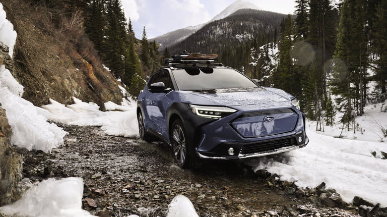 a blue Solterra driving on a snowy mountain trail