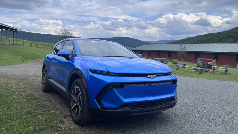 A blue Chevy Equinox EV in three-quarter view on a farm
