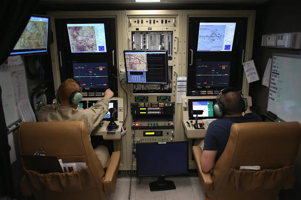 Two men operate an unmanned Predator aircraft from a flight operations center near the Mexican border.