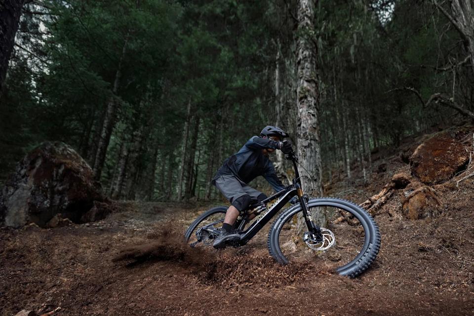 A rider making a turn in the forest while riding the Amflow PL Carbon Pro