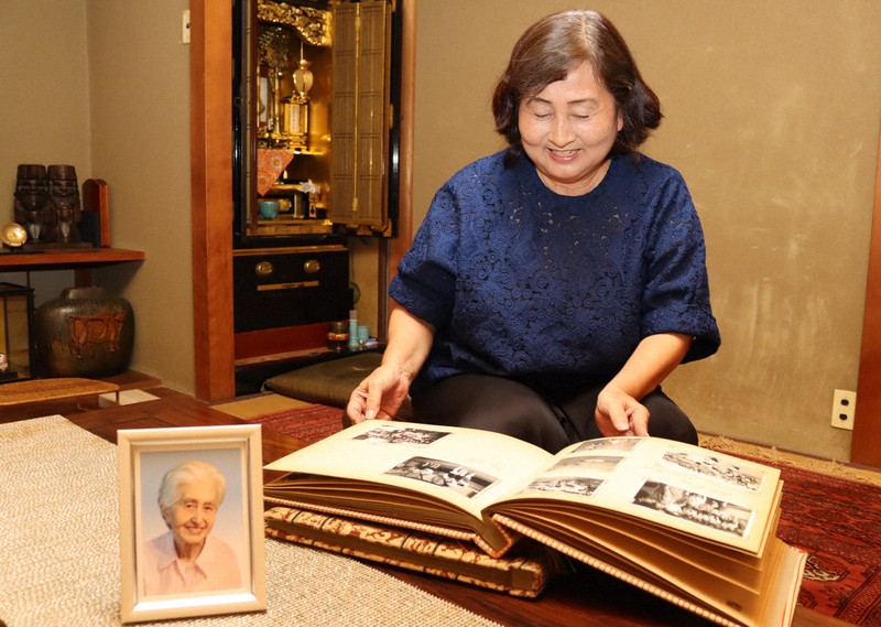 母・加口嘉子さんのアルバムをめくる敦子さん。左の写真は嘉子さん=京都市で2025年7月28日午後3時31分、木谷郁佳撮影