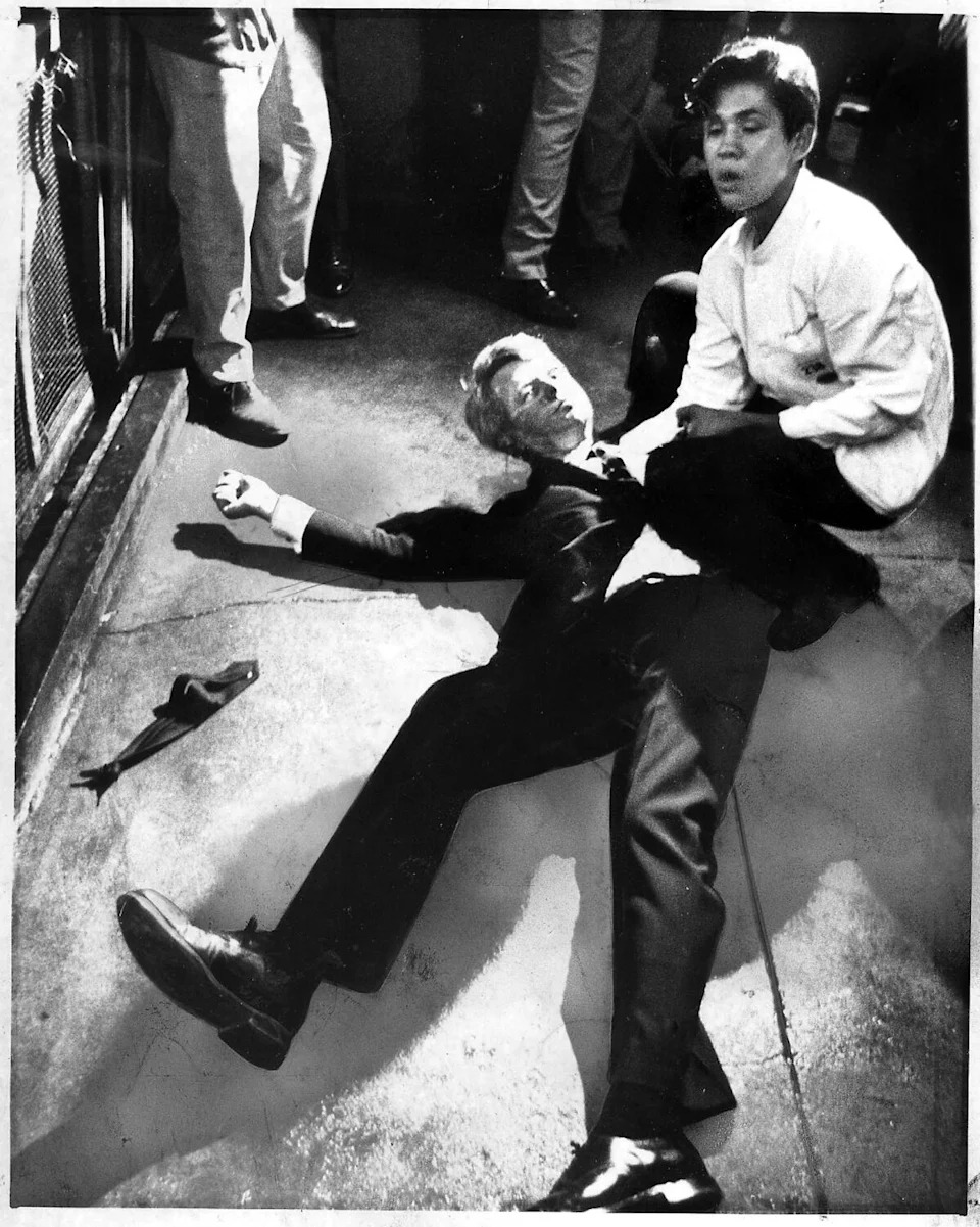 Presidential candidate Robert F. Kennedy lies on the floor at the Ambassador Hotel while another man kneels next to him.