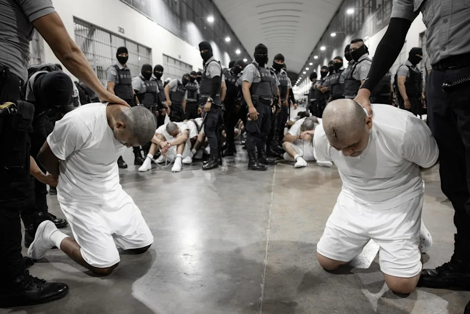 Inmates kneel on the ground at CECOT.