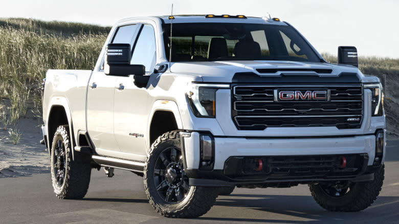 A white 2025 Sierra 2500 HD AT4 in front of marsh grass