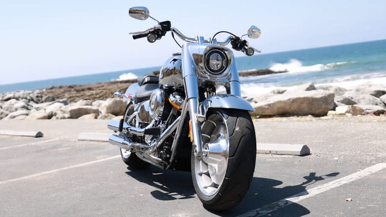 A chrome Harley-Davidson Fat Boy parked next to the sea