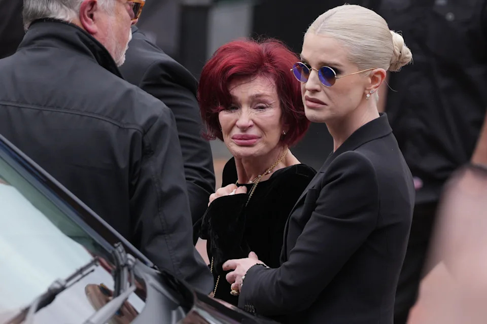 Sharon Osbourne and Kelly Osbourne stop to view tributes to the late Ozzy Osbourne from fans at Black Sabbath Bench and Bridge as his funeral cortege travels through his home city of Birmingham on July 30, 2025 in Birmingham, England.