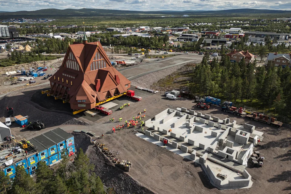 An aerial view of a church that is being moved as it approaches a newly-poured concrete foundation.