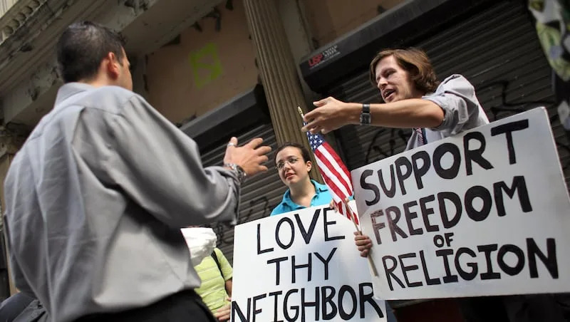 Matt Sky, right, and Julia Lundy, center, explain their support for the proposed site for an Islamic cultural center to a man who was walking by, Friday, Aug. 27, 2010, in New York.