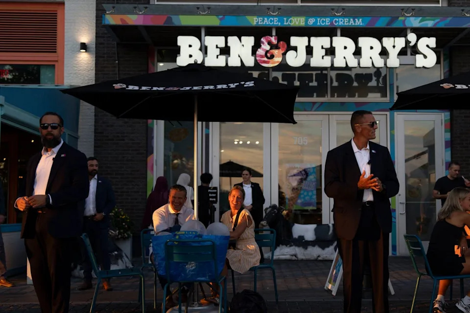 The Hegseths sit outside a branch of Ben and Jerry's in Washington, D.C., on Thursday August 14 as their security detail watches over them (Getty)